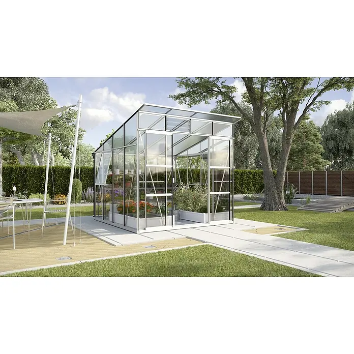 Vitavia Gewächshaus Freya 7600 Plus - Außenmaß inkl. Dachüberstand (B x T): 292 x 258 cm, Wandstärke: 3 mm, Aluminium - Ein modernes Gewächshaus mit klarem Glas und silbernem Rahmen steht in einem üppigen Garten. Pflanzen und Blumen gedeihen im Inneren des Gewächshauses.