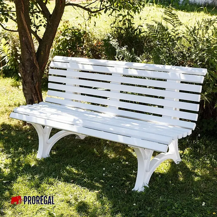 Proregal Gartenbank Jamaika 3-Sitzer aus Kunststoff - Weiß - Eine weiße Gartenbank aus Holz mit gusseisernen Beinen steht auf einer Rasenfläche unter einem Baum im Garten.