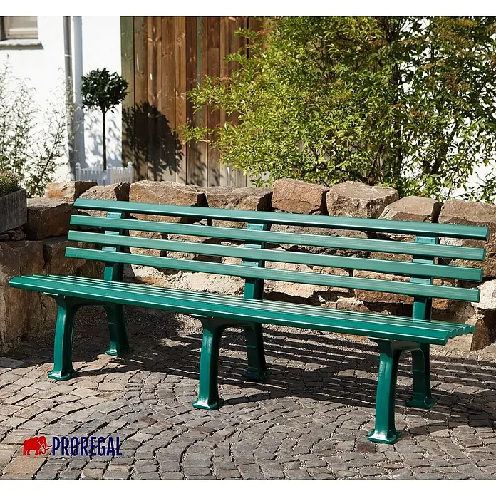 Proregal Gartenbank Antigua 4-Sitzer aus Kunststoff - Grün - Grüne Parkbank mit Lattenrost und robusten Beinen vor steinerner Mauer. Ideal für Gärten und Parks, bietet bequemen Sitzplatz im Freien.