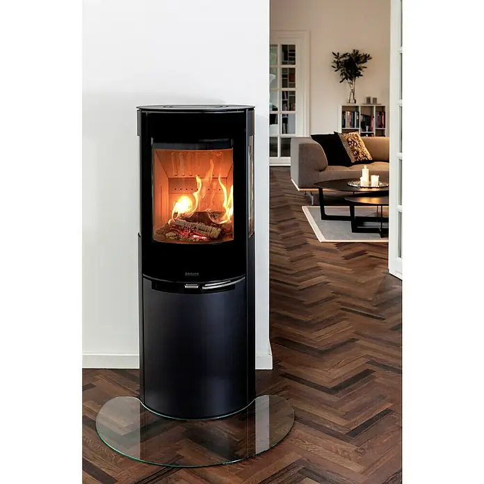 Aduro Kaminofen 9-5 Lux Air - 8 kW, Raumheizvermögen: 350 m³, Material Verkleidung: Stahl, Schwarz - Das Bild zeigt einen eleganten, schwarzen Adura Kaminofen mit Glasbodenplatte, der ein gemütliches Ambiente in einem stilvollen Wohnraum schafft.