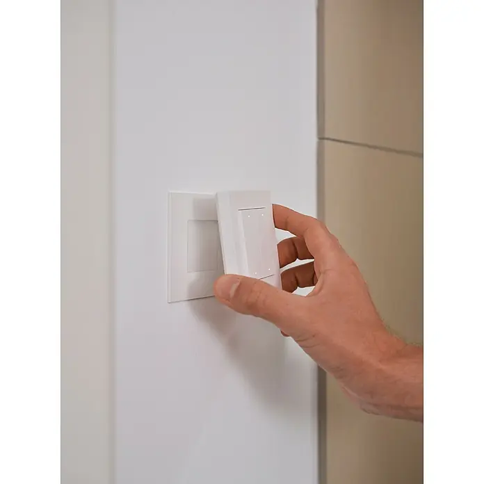 Osram Smart+ Schalter 4G matter - Weiß, Innen - Nahaufnahme eines Mannes, der einen weißen Lichtschalter an einer weißen Wand montiert.