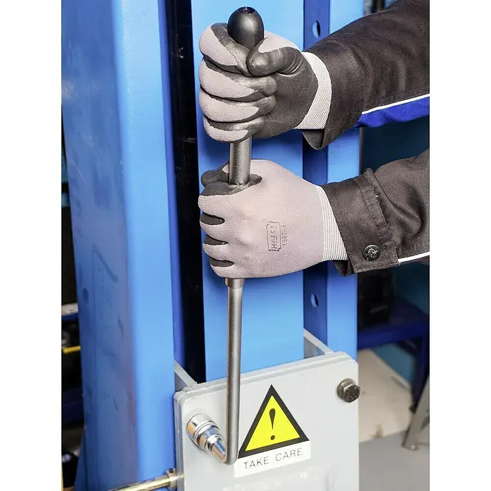 Hazet Teleskop-Radmutternschlüssel 772 - Teleskopierbar: 303 mm - 535 mm, Antriebsgröße: ½″ - Ein Mann bedient eine hydraulische Werkstattpresse mit einer schwarzen Kugel am Hebel und trägt dabei Schutzhandschuhe.