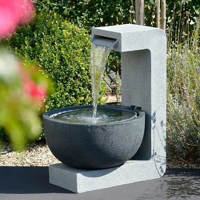 Dobar Kunststeinbrunnen - 52 x 44 x 65 cm - Ein Brunnen mit einer Wasserschale und einem Wasserfall aus einem grauen Steinturm im Garten, der Ruhe und natürliche Schönheit vereint.