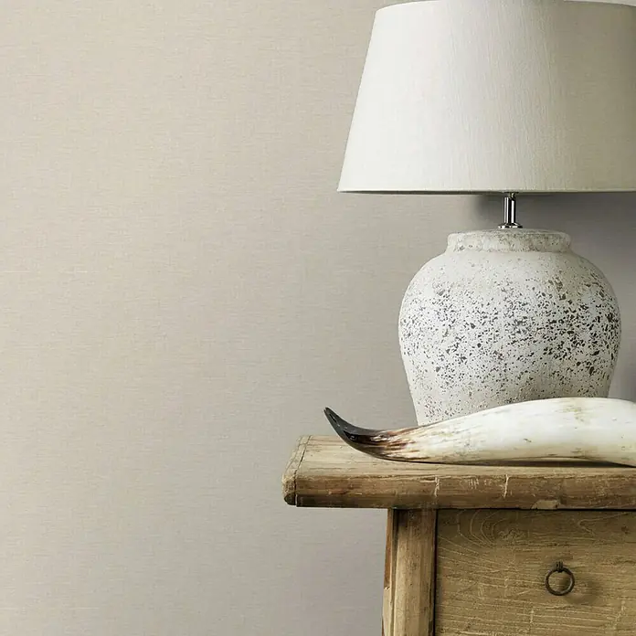 Rasch Vliestapete - Beige, Uni, 10,05 x 0,53 m, Gewebestruktur - Eine rustikale Nachttischlampe mit einem Lampenschirm aus Stoff und einem dekorativen Horn für ein gemütliches Ambiente.
