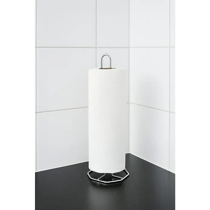 Venus Soporte para rollos Ancona - Cromo - Portarrollos de cocina con un rollo de toallas de papel sobre una encimera oscura contra un protector contra salpicaduras de azulejos blancos.