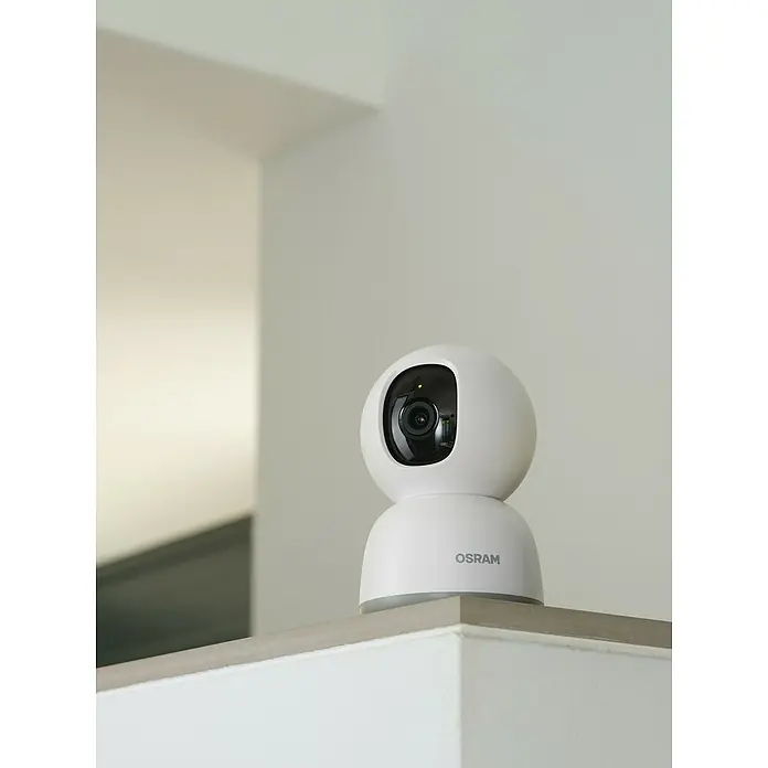 Osram Smart+ Überwachungskamera 360 - Passend für: Alarmsystem, Smart Home System - Nahaufnahme einer weißen OSRAM Überwachungskamera auf einem Sims mit Blick auf ein modernes, minimalistisches Interieur.