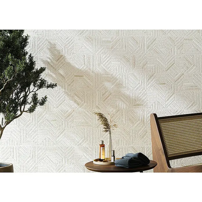 Revestimiento de pared Nomad Decor - 30 x 90 cm, Lino, Rectificado, Relieve - Una habitación con una pared decorada con azulejos geométricos, acentuada por una planta y una silla con asiento de mimbre.
