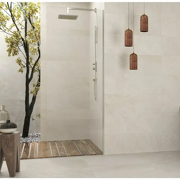 Revestimiento de pared Aurea - 30 x 90 cm, Crema, Rectificado - Elegante baño con ducha estilosa, suelo de madera e iluminación decorativa, creando un ambiente relajante. Los azulejos claros añaden un toque moderno.