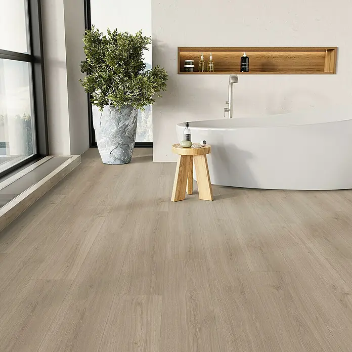 Parador Vinylboden Basic 5.3 - Eiche Regent grau, Landhausdiele, 1.209 x 225 x 5,3 mm - Ein Badezimmer mit hellem Holzboden, einer freistehenden Badewanne und einem Holzhocker mit Pflegeprodukten. Die natürliche Beleuchtung ist schön.