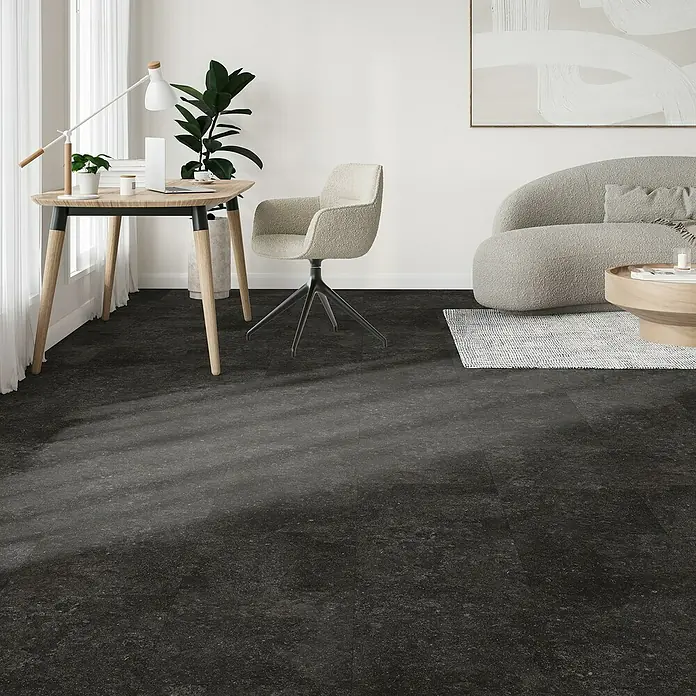 Parador Designboden Modular One - Granit anthrazit, Landhausdiele, 853 x 400 x 8 mm - Elegantes Interieur mit schwarzem Fliesenboden, der einen modernen Schreibtisch, Stuhl und ein graues Sofa perfekt ergänzt.