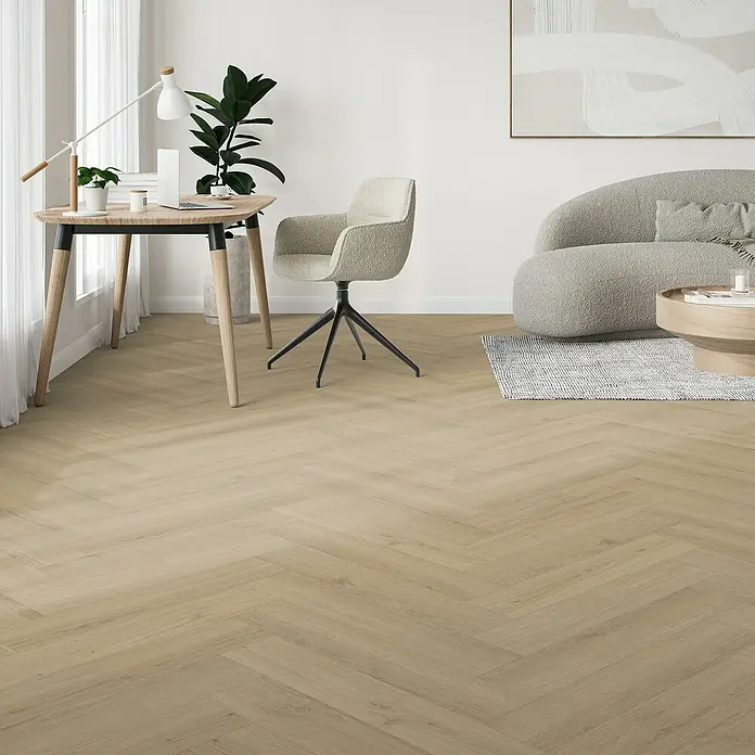 Parador Vinylboden Trendtime 3 - Eiche Regent beige, Fischgrät, 730 x 146 x 5 mm - Büro-Szene mit hellem Holzparkettboden, Schreibtisch, Stuhl und Sofa in einem hellen Raum. Das Parkett verleiht dem Raum Wärme und Stil.