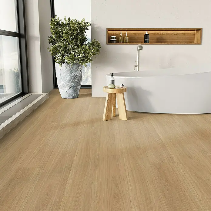 Parador Vinylboden Basic 5.3 - Eiche Oxford natur, Landhausdiele, 1.209 x 225 x 5,3 mm - Badezimmer mit hellem Holzboden, weißer Badewanne und Pflanze. Der Holzboden verleiht dem Raum Wärme und Eleganz.