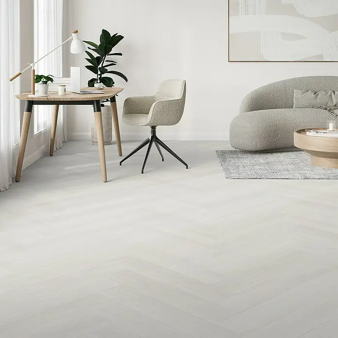 Parador Vinylboden Trendtime 3 - Eiche Oxford weiß, Fischgrät, 730 x 146 x 5 mm - Elegantes Interieur mit hellem Holztisch, stilvollem Stuhl und einem komfortablen Sofa, das eine einladende Atmosphäre schafft.