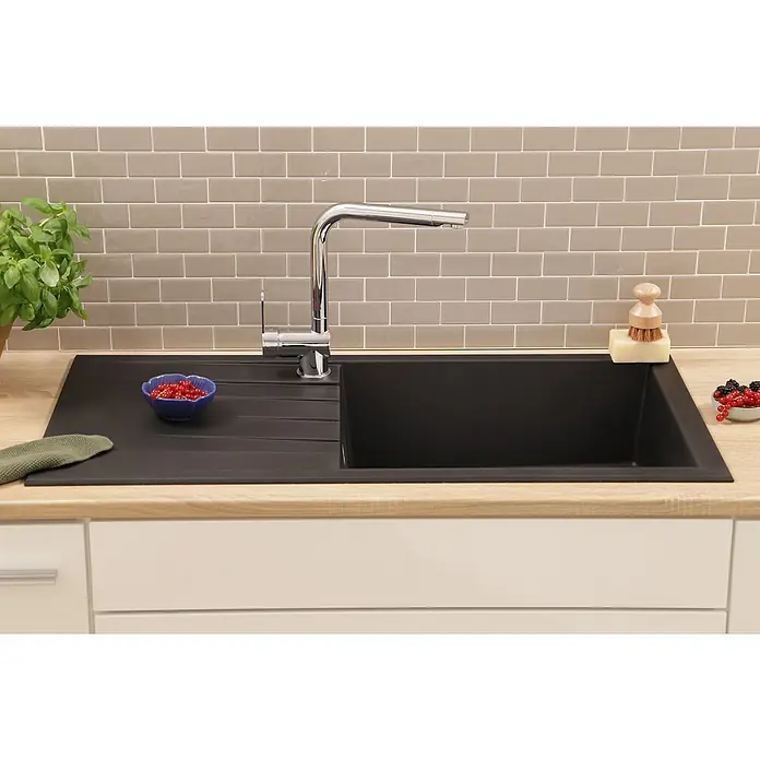 Respekta Einbauspüle Houston - 100 x 50 cm, Schwarz, Anzahl Becken: 1 Stk. - Küchenspüle mit Abtropffläche und Armatur, dekoriert mit Beeren, Spülbürste und Basilikum, vor einer grauen Backsteinwand.