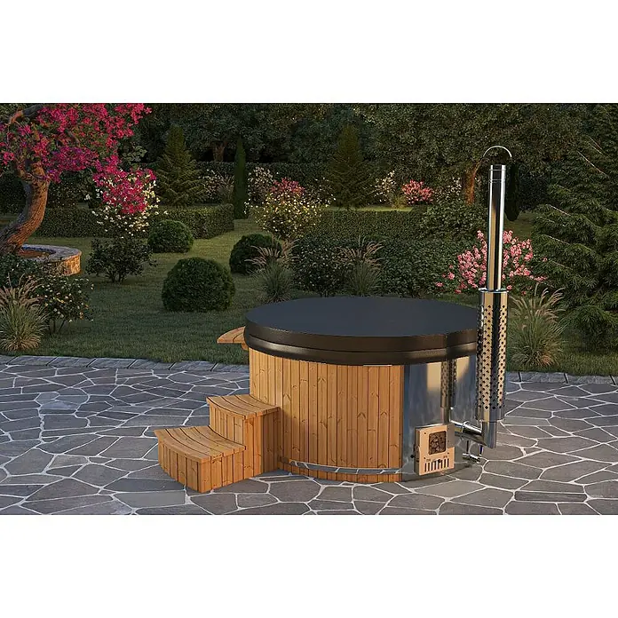 FinnTherm Hot Tub Stockholm - 200 cm, Nordische Holz, Naturbelassen - Eine hölzerne Badetonne mit integriertem Ofen und Treppe steht im Garten, umgeben von üppiger Vegetation.