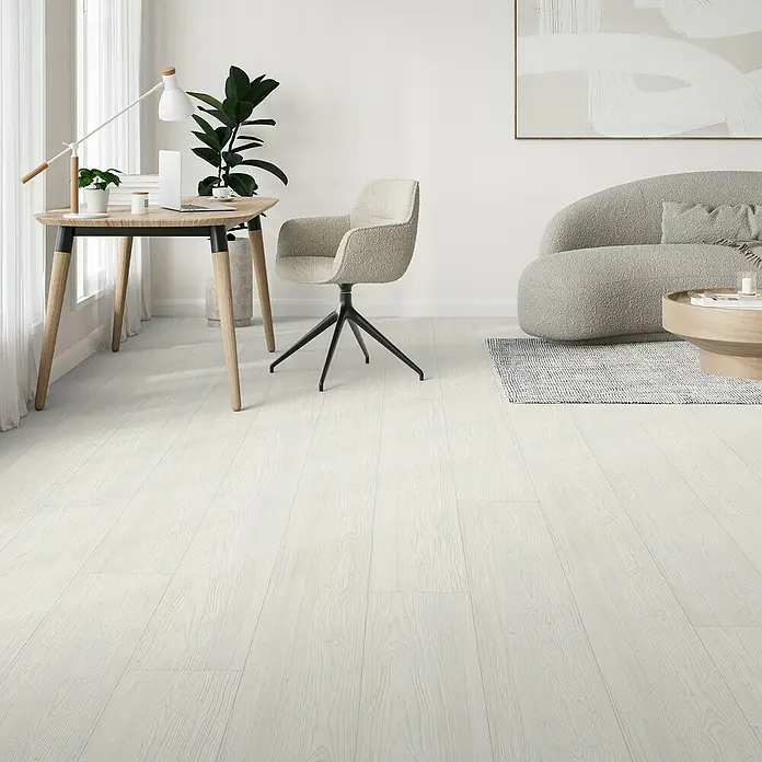 Parador Designboden Modular One - Lärche Apollo weiß, Landhausdiele, 2.200 x 235 x 8 mm - Helles Interieur mit modernem Schreibtisch, Stuhl und Sofa. Der Fokus liegt auf dem weißen Holzboden, der dem Raum eine elegante Note verleiht.
