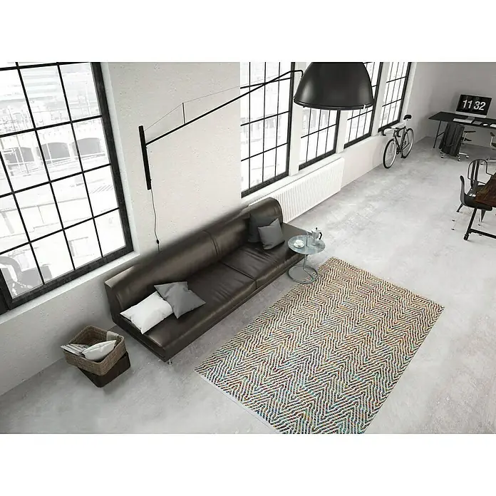 Kayoom Flachgewebeteppich Cocktail 400Bunt, 150 x 80 cm, 100% Baumwolle - Wohnzimmer-Interieur mit einem braunen Ledersofa, einem farbenfrohen Teppich mit Zickzackmuster und großen Fenstern für ein modernes Ambiente.