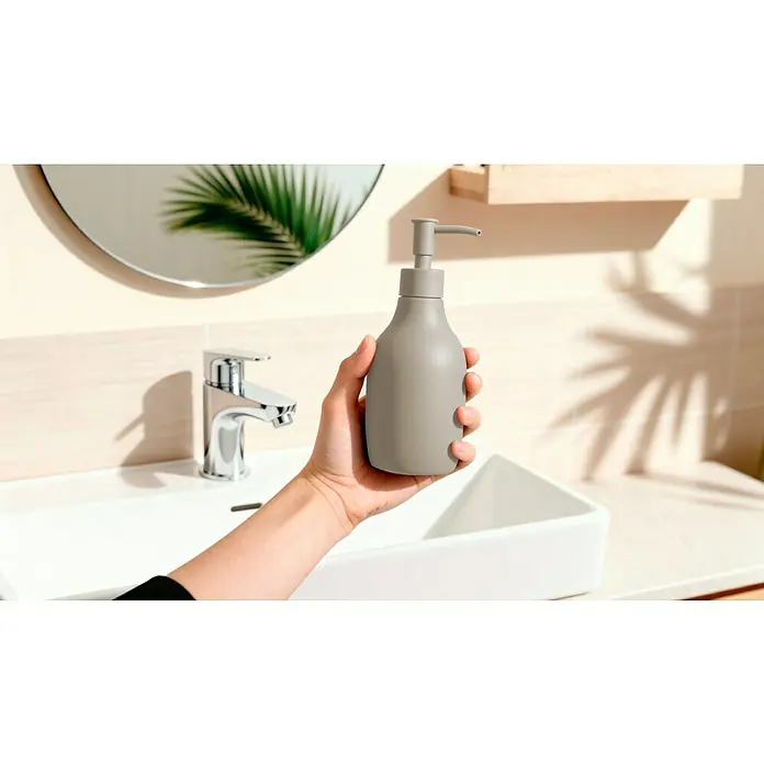 Venus Flakoni Seifenspender - Polyresin, Beige - Eine Hand hält einen grauen Seifenspender vor einem Waschbecken im Badezimmer. Der Fokus liegt auf dem stilvollen Spender.