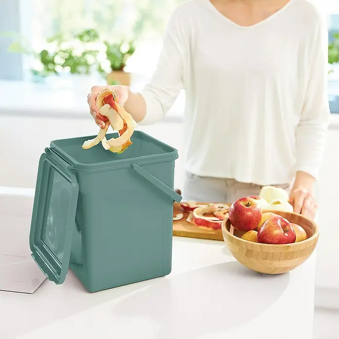 Proregal Standard-Mülleimer Robuster Abfalleimer mit geruchsdichtem Deckel - 9 l, Kunststoff, Grün - Frau entsorgt Apfelreste in einem grünen Komposteimer mit Deckel. Küchen-Komposter für Bioabfälle und zur Reduzierung von Küchenmüll.