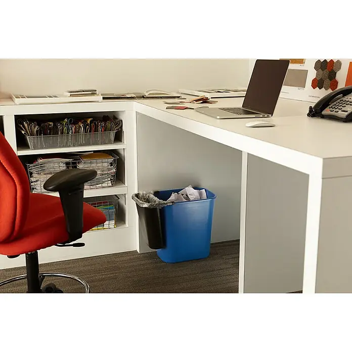 Proregal Standard-Mülleimer Rubbermaid rechteckiger Abfallbehälter aus Polyethylen - 26,6 l, Kunststoff, Blau mit Recyclingsymbol - Nahaufnahme eines blauen Papierkorbs unter einem Schreibtisch, der für eine saubere Büroumgebung sorgt.