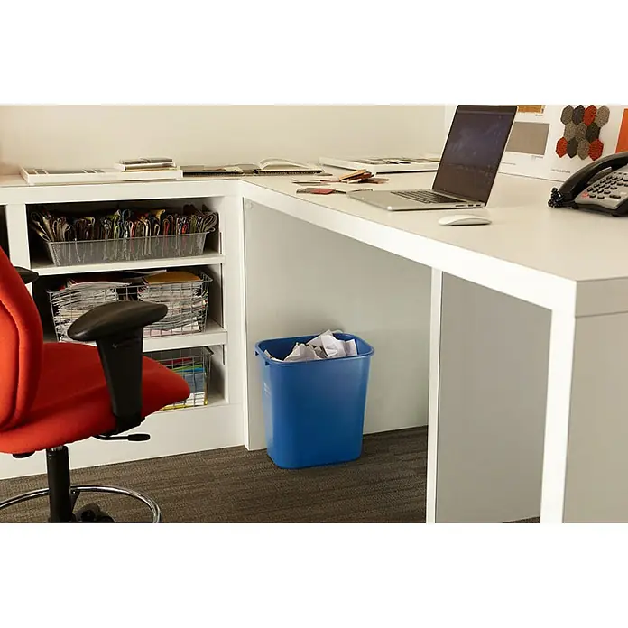 Proregal Standard-Mülleimer Rubbermaid rechteckiger Abfallbehälter aus Polyethylen - 26,6 l, Kunststoff, Blau mit Recyclingsymbol - Büroumgebung mit einem Laptop, einem roten Bürostuhl und einem blauen Papierkorb unter dem Schreibtisch, der mit Papier gefüllt ist.