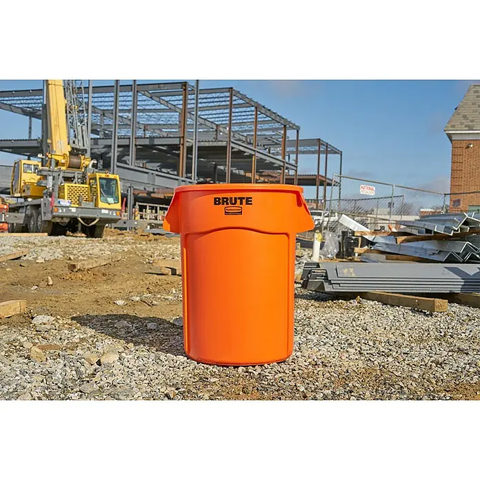 Proregal Standard-Mülleimer Rubbermaid Brute runde Mehrzwecktonne mit Belüftungskanälen - 166,5 l, Kunststoff, Orange - Aufnahme eines orangefarbenen "Brute"-Mülleimers von Rubbermaid auf einer Baustelle, der für seine Robustheit bekannt ist.