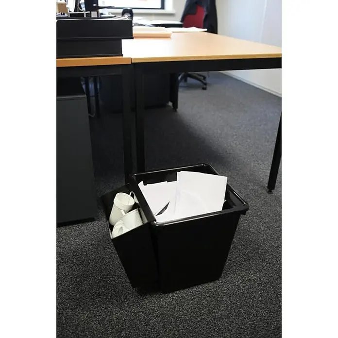 Proregal Papierkorb viereckig & kegelförmig - 27 l, Kunststoff, Schwarz - Ein schwarzer Abfalleimer unter einem Schreibtisch mit Papier und weißen Pappbechern, der in einem Büro steht.