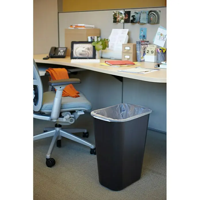 Proregal Standard-Mülleimer Rubbermaid rechteckiger Abfallbehälter - 39 l, Kunststoff, Schwarz - Büro-Szene mit einem schwarzen Mülleimer mit Müllbeutel, der neben einem Bürostuhl unter einem Schreibtisch steht.