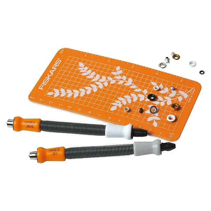 Fiskars Ösenstanzer - 2 -tlg. - Nahaufnahme eines Fiskars-Lochwerkzeug-Sets mit Ösen und einer orangefarbenen Schneidematte.