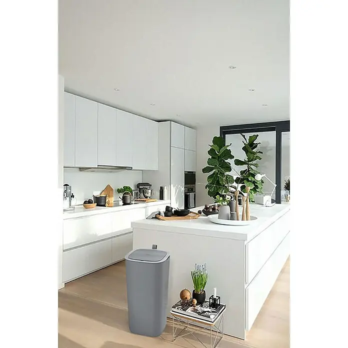 Proregal Sensormülleimer Moderner quadratischer Abfalleimer mit Smart Sensor - 30 l, Kunststoff, Grau - Der graue Abfalleimer aus Kunststoff in der Küche. Er steht neben einem kleinen Tisch mit Dekoration.