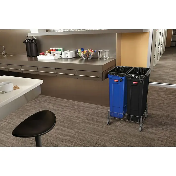 Proregal Standard-Mülleimer Rubbermaid Slim Jim Mülleimer mit Belüftungskanälen - 87 l, Kunststoff, Schwarz - Eine blaue und eine schwarze Mülltonne von Rubbermaid stehen auf einem Rollwagen in einem Büroraum.