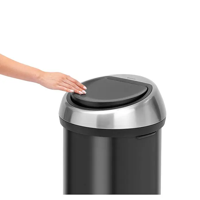 Proregal Standard-Mülleimer Brabantia Abfallbehälter mit Soft-Touch-Öffnung - 60 l, Metall, Matt Schwarz-Matt Edelstahl - Eine Hand berührt den Deckel des runden, schwarzen Brabantia-Mülleimers mit silbernem Deckel auf einem weißen Hintergrund.