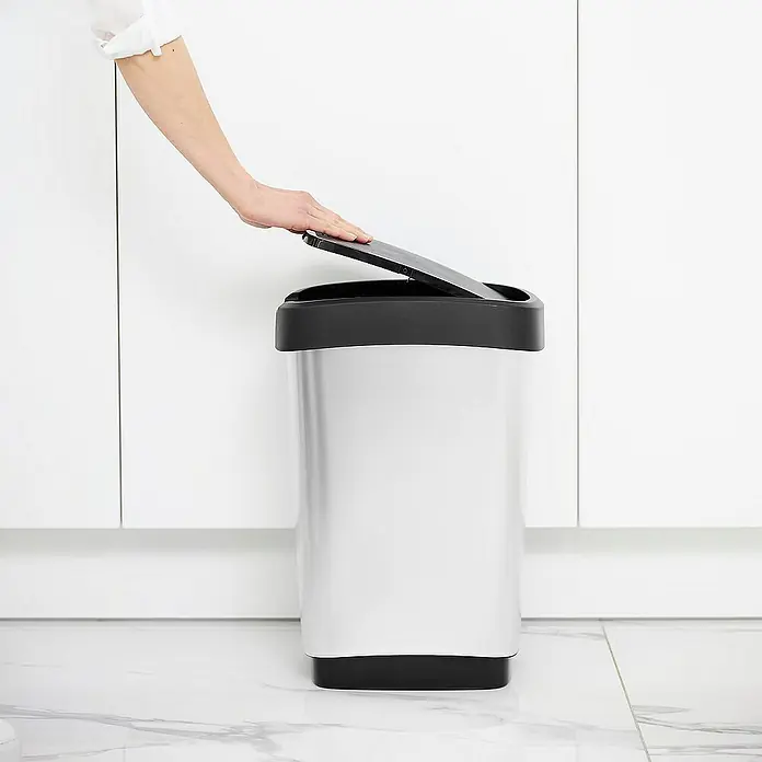 Proregal Standard-Mülleimer Klassischer Abfalleimer für Innenbereich - 25 l, Kunststoff, Silber-Schwarz - Silberfarbener Abfallbehälter mit schwarzem Deckel wird von einer Person geöffnet, minimalistisches Küchendesign im Hintergrund.