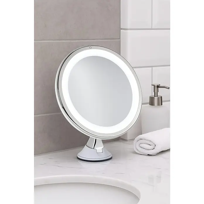 Venus Espejo cosmético Linda - Redonda, Aumento 2: 1.000 % - Primer plano de un espejo de maquillaje redondo con luz LED en un tocador de baño con jabón y toalla.