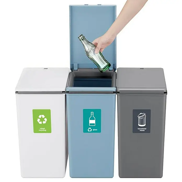 Proregal Sensormülleimer Moderner quadratischer Abfalleimer mit Touch-Bar-Deckel - 20 l, Kunststoff, Grau - Drei EKO-Mülleimer zur Mülltrennung, wobei eine Hand eine Glasflasche in den blauen Behälter wirft.