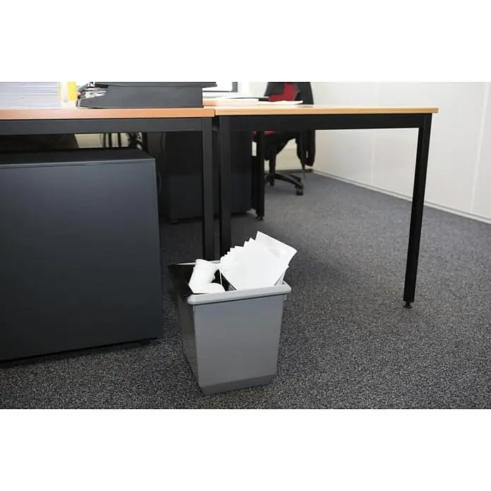 Proregal Papierkorb viereckig & kegelförmig - 21 l, Kunststoff, Grau - Grauer Papierkorb mit Papiermüll unter einem Schreibtisch in einem Büro. Ordnungsgemäße Entsorgung von Büromaterial im modernen Büroalltag.