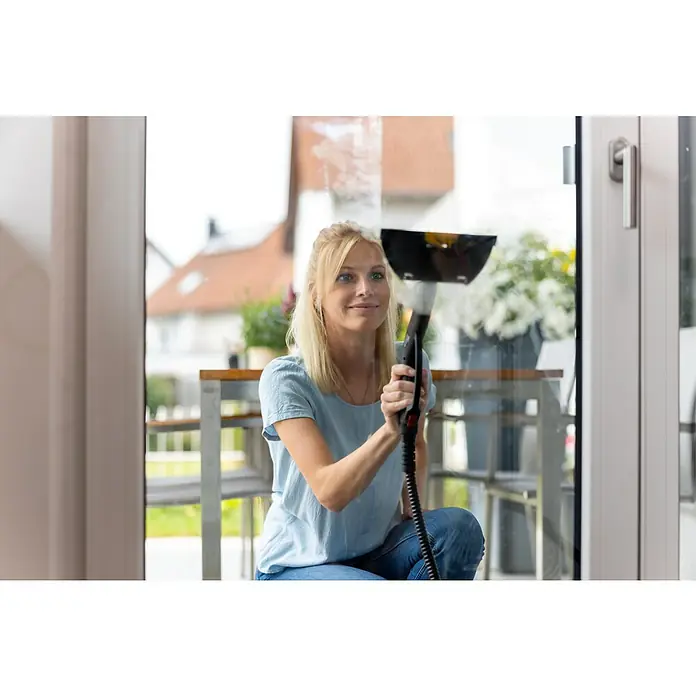 Wagner Dampfreiniger Power Steamer 915 E - 1.500 kW, Aufheizzeit: 7 min, Behältervolumen: 1,2 l - Eine blonde Frau reinigt Fenster mit einem Fenstersauger, der für streifenfreie Sauberkeit sorgt und Zeit spart.