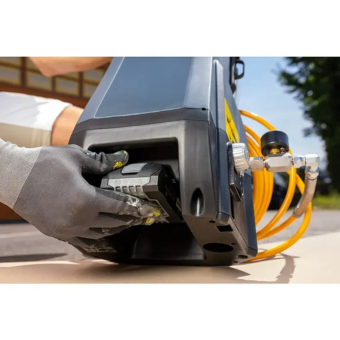 Akku-Farbsprühsystem - 18 V, 1 Akku, 4 Ah, Max. Fördermenge: 0,9 l/min - Der Bosch Akku-Kompressor in Aktion: Ein Handwerker setzt einen Bosch-Akku in das Gerät ein, bereit für den nächsten Einsatz.