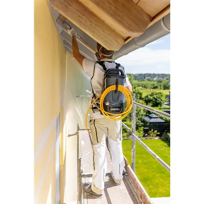 Akku-Farbsprühsystem - 18 V, 1 Akku, 4 Ah, Max. Fördermenge: 0,9 l/min - Maler mit SprayPack XT Farbspritzgerät bei der Arbeit auf einem Gerüst im Freien.