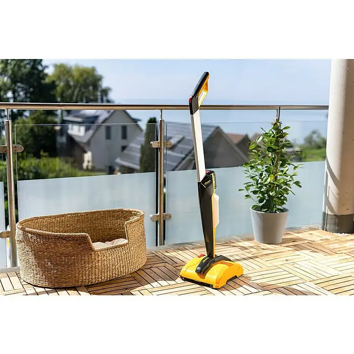 Wagner Akku-Terrassenreiniger Levaro PowerBrush 18V - 18 V, Ohne Akku, 700 l - Ein gelber und schwarzer Wagner-Bodenreiniger steht auf einer Terrasse mit Holzfliesen, neben einem Korb und einer Topfpflanze.