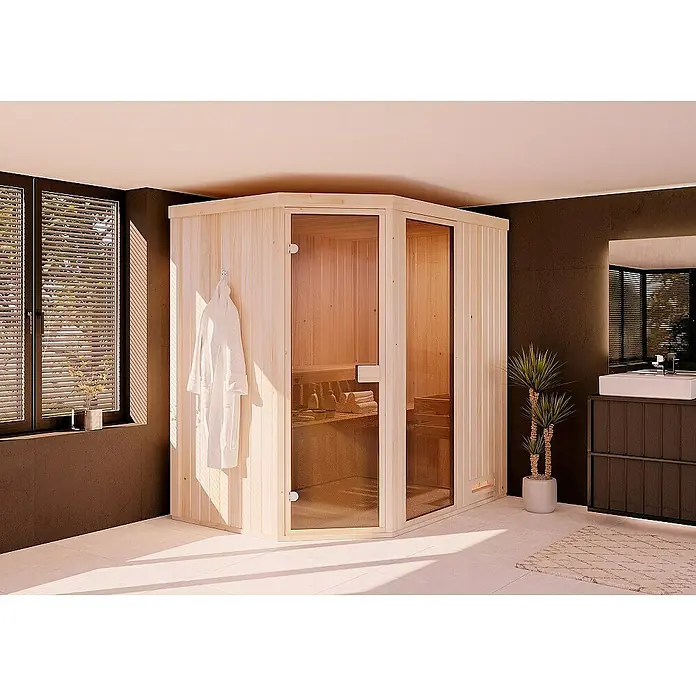 FinnTherm Massivholzsauna Pearl - L x B x H: 144 x 175 x 199 cm - Ein Ecksauna-Modell mit Glastüren in einem Badezimmer, neben einem Fenster und einem Waschtischmöbel. Der Innenraum ist einladend hell.