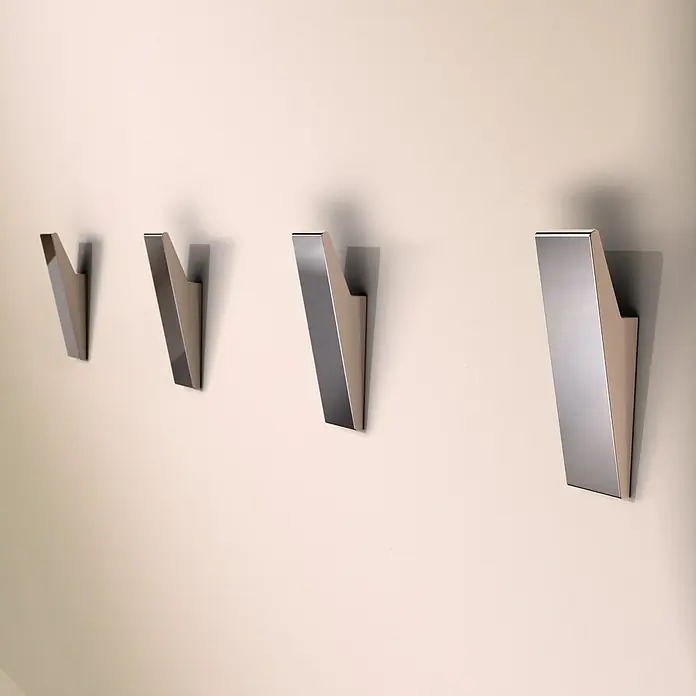 Designfabrik Hamburg Handtuchhaken - 4 Stk., Chrom, Glänzend - Eine Reihe von vier modernen, metallenen Kleiderhaken an einer hellen Wand, die ein stilvolles und funktionales Design zeigen.