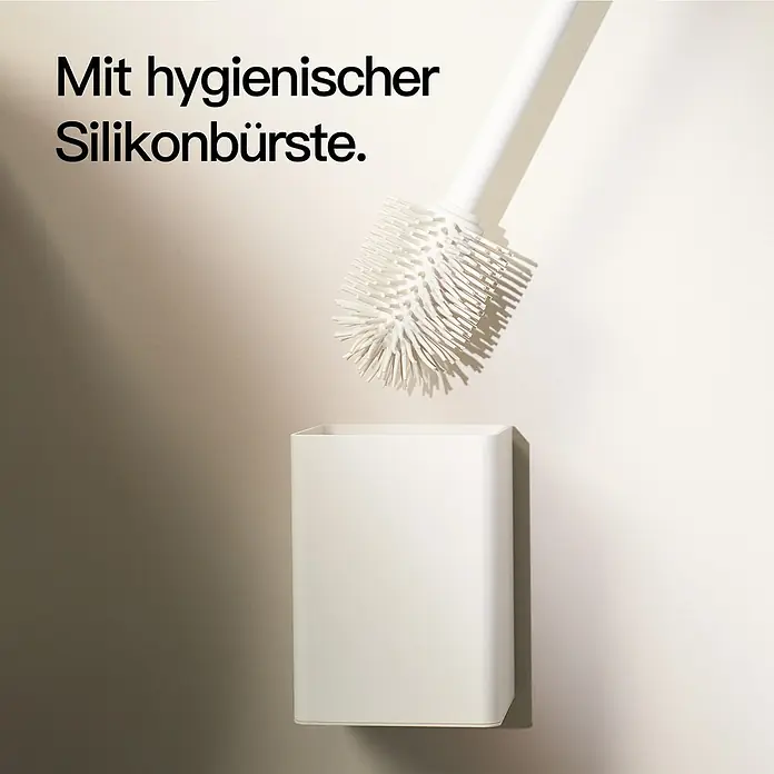Designfabrik Hamburg WC-Bürstengarnitur - Aluminium, Weiß - Eine Toilettenbürste mit einem weißen Griff und Silikonborsten wird in einen passenden, an der Wand montierten Halter gestellt.