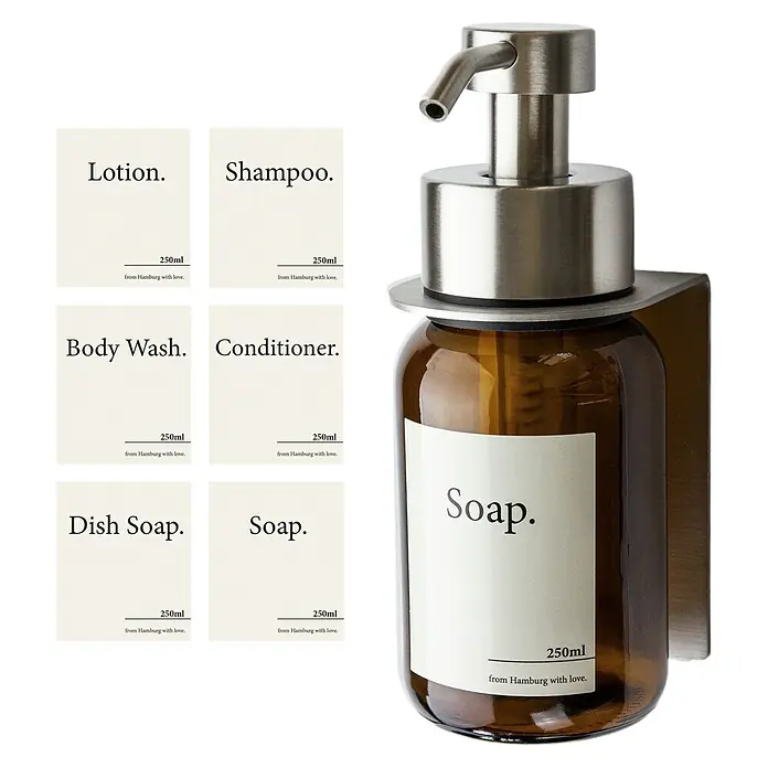 Designfabrik Hamburg Seifenspender - Edelstahl, Silber/Braunglas, Wandmontage - Das Bild zeigt ein Seifenspender-Set mit Lotion, Shampoo, Duschgel, Spülmittel, Seife, Conditioner und einer bernsteinfarbenen Glasflasche mit Seife.