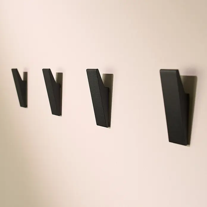 Designfabrik Hamburg Handtuchhaken - 4 Stk., Schwarz, Matt - Wandhaken aus schwarzem Metall im minimalistischen Design, die stilvoll an einer hellen Wand befestigt sind.