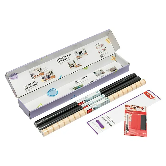 D-c-fix Klebefolie Kreativ-Kit - 3 Stk., 2 m x 67,5 cm, Seidenmatt Schwarz/Wooden Slats, Selbstklebend - Eine offene Produktverpackung von d-c-fix, die verschiedene Rollen Designfolie, ein Falt-Schablone und ein Applikations-Set für Folien zeigt.