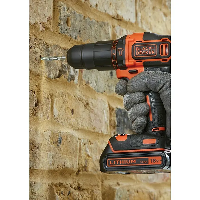 Black+Decker Taladro atornillador percutor de batería BDCHD18KB - 18 V, 2 baterías, 1,5 Ah, 40 Nm - Un taladro inalámbrico Black+Decker perforando una pared de ladrillos, destacando su potencia y facilidad de uso.