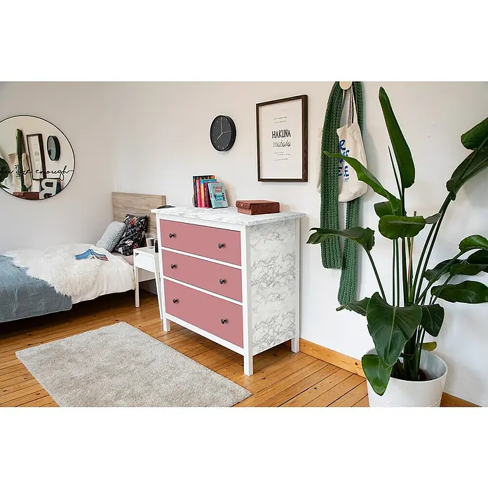 D-c-fix Klebefolie Kreativ-Kit - 3 Stk., 2 m x 67,5 cm, Marmi Grau/Uni Seidenmatt Ash Rose, Selbstklebend - Eine moderne Kommode mit marmorierter Oberfläche und rosa Schubladen steht in einem hellen Raum mit Holzboden.