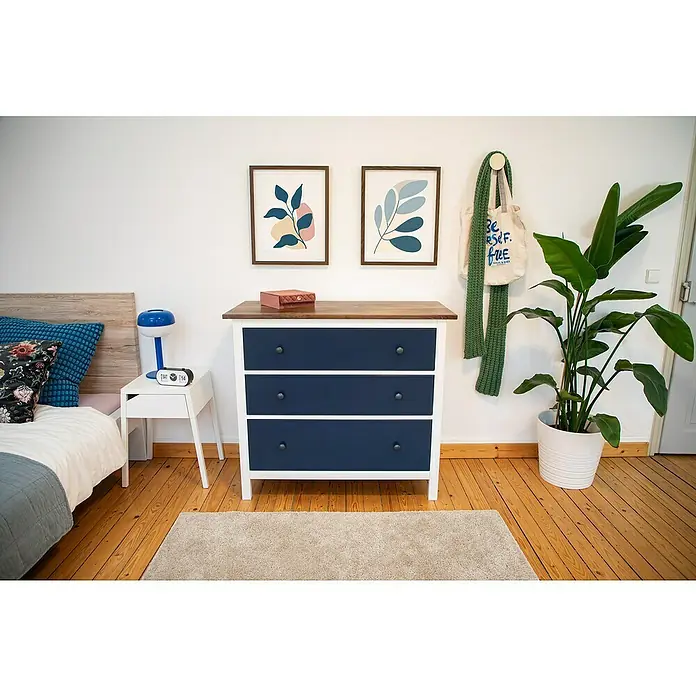 D-c-fix Klebefolie Kreativ-Kit - 3 Stk., 2 m x 67,5 cm, Flagstaff Oak/Uni Seidenmatt Midnight Navy Blue, Selbstklebend - Geräumiges Schlafzimmer mit einer Kommode in Marineblau, die Stauraum bietet. Dekorative Elemente und Zimmerpflanzen ergänzen den Raum.