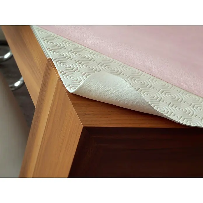 D-c-fix Tischdecke Padua - 1,4 x 15 m, Rechteckig, Kunststoff, Weiß - Nahaufnahme einer rutschfesten Tischdecke mit rosa Oberseite und weißer Unterseite mit sechseckigem Muster, die auf einem Holztisch liegt.